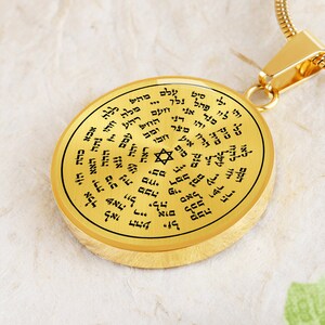 May include: A gold-toned pendant necklace with a round charm featuring a Star of David and Hebrew text. The charm is surrounded by a circle of Hebrew text.