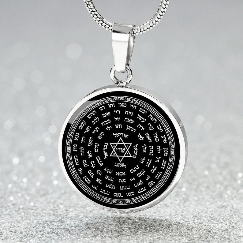 May include: A silver chain necklace with a round pendant featuring a black background and a silver Star of David in the center. The pendant is inscribed with Hebrew text in a circular pattern.