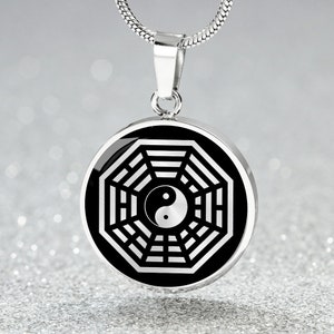 Puede incluir: Un collar de plata con un colgante octogonal de plata que contiene un s&iacute;mbolo yin yang en blanco y negro. El colgante est&aacute; en una cadena de serpiente de plata.