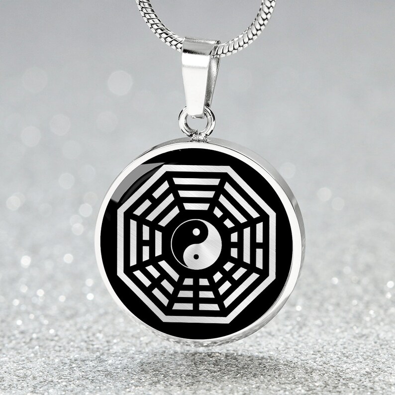 Puede incluir: Un collar de plata con un colgante octogonal de plata que contiene un s&iacute;mbolo yin yang en blanco y negro. El colgante est&aacute; en una cadena de serpiente de plata.