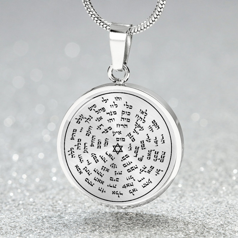 May include: Silver pendant necklace with a round charm featuring a Star of David and Hebrew text. The charm is engraved with a circular pattern of Hebrew letters.