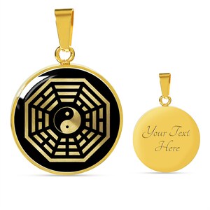 Puede incluir: Collar con colgante dorado sobre fondo negro que presenta un s&iacute;mbolo yin yang dorado dentro de un s&iacute;mbolo de ocho trigramas dorado. La parte posterior del colgante es de oro liso con el texto "Your Text Here".