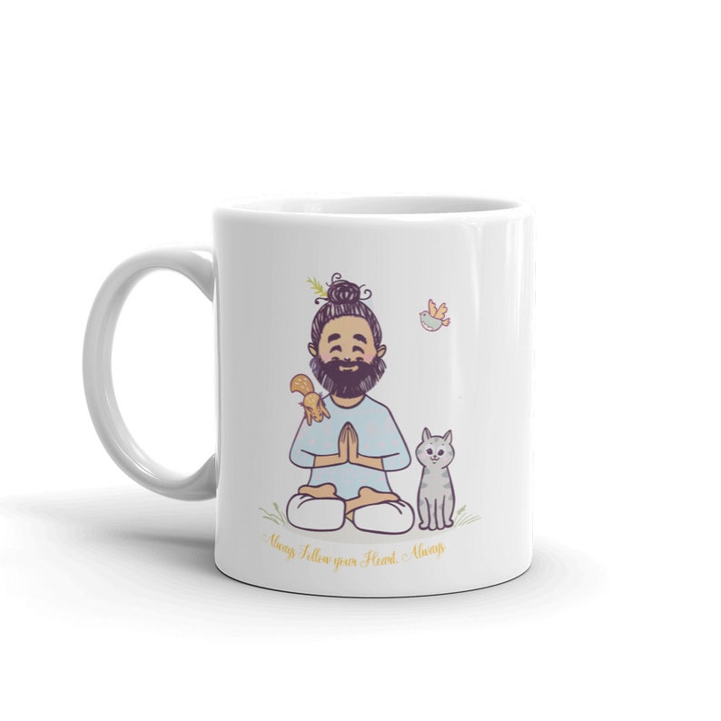 Puede incluir: Taza de cer&aacute;mica blanca con una ilustraci&oacute;n de dibujos animados de un hombre con barba meditando con una ardilla y un gato. El texto "Always follow your Heart - Always" est&aacute; impreso en la parte inferior de la taza.