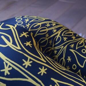 May include: Black leggings with a yellow geometric pattern. The pattern features leaves, stars, and circles.