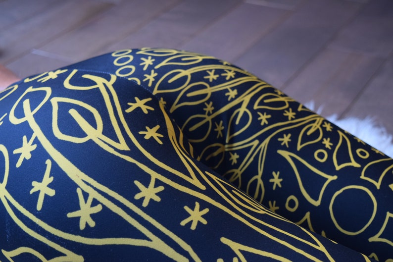 May include: Black leggings with a yellow geometric pattern. The pattern features leaves, stars, and circles.