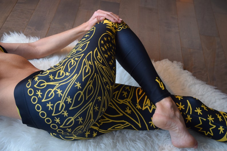 May include: Black leggings with a gold mandala pattern. The leggings are made of a stretchy, comfortable fabric and are perfect for yoga, running, or everyday wear.