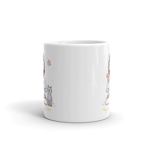 Puede incluir: Taza de caf&eacute; de cer&aacute;mica blanca con una ilustraci&oacute;n de dibujos animados de una persona sentada con un gato y una mariposa. El texto "Always be kind" est&aacute; impreso en la taza.