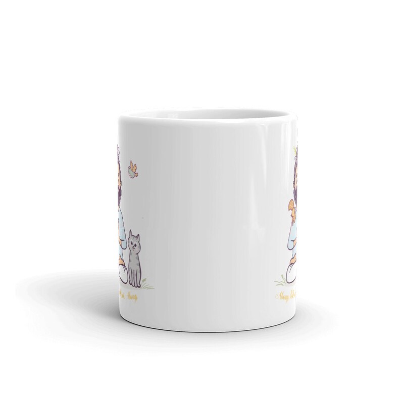 Puede incluir: Taza de caf&eacute; de cer&aacute;mica blanca con una ilustraci&oacute;n de dibujos animados de una persona sentada con un gato y una mariposa. El texto "Always be kind" est&aacute; impreso en la taza.