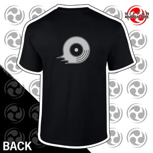 May include: Black t-shirt with a grey graphic of a stylized record on the back. The text "NIPPON MANUFACTURE" is printed in white on the top right corner of the shirt.