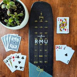 Planche de ski cribbage unique, livrée avec 9 piquets en métal et un jeu de cartes.