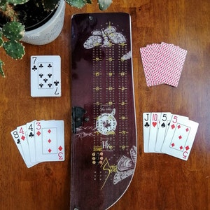 Prior Cribbage Board, est livré avec 9 chevilles en métal et un jeu de cartes.