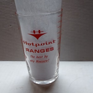 May include: A clear glass measuring cup with red markings and the text "Hotpoint Ranges The best by any Measure!" printed on the side.