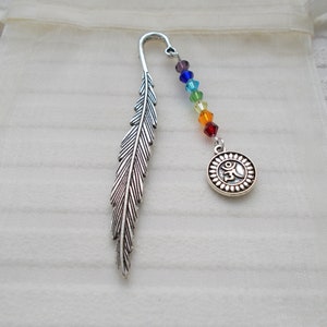 May include: Silver feather bookmark with a rainbow colored beaded chain and a silver charm with an Om symbol.