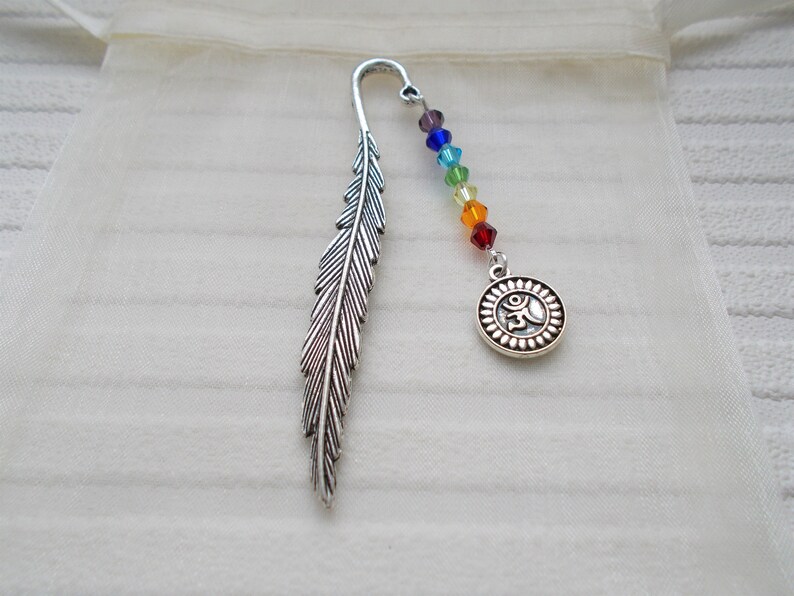 May include: Silver feather bookmark with a rainbow colored beaded chain and a silver charm with an Om symbol.