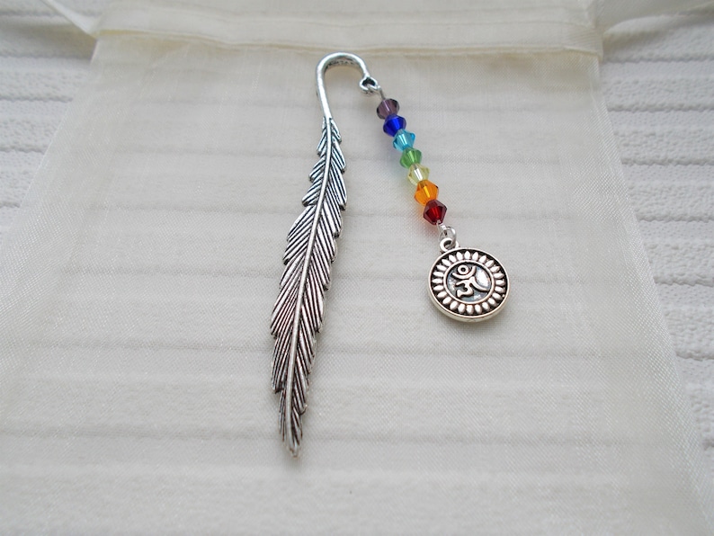 May include: Silver feather bookmark with a rainbow colored beaded chain and a silver charm with an Om symbol.