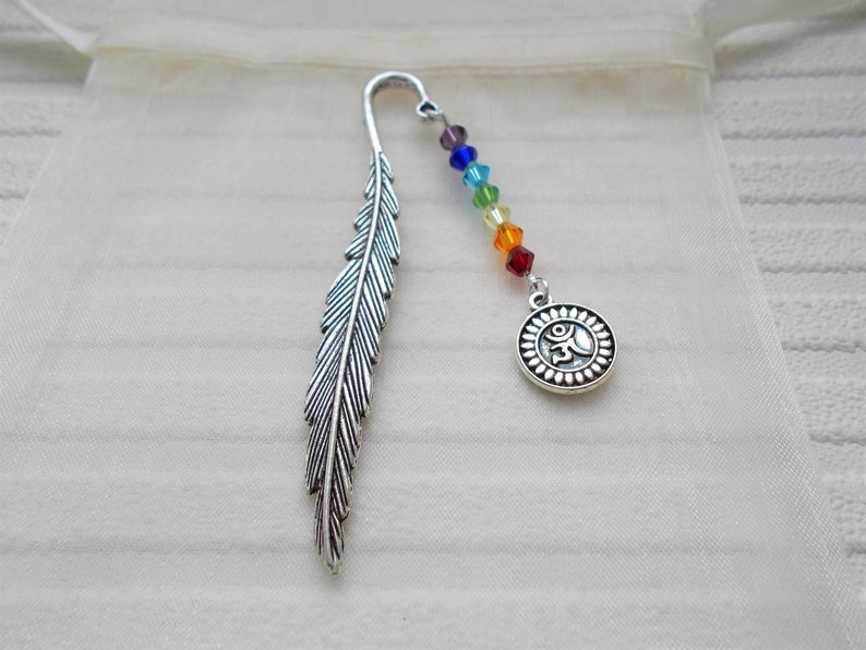 May include: A silver feather bookmark with a rainbow colored beaded chain and a silver charm with an Om symbol.