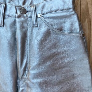 Peut inclure: Pantalon argent&eacute; m&eacute;tallis&eacute; avec fermeture boutonn&eacute;e et zipp&eacute;e. Le pantalon a une conception classique &agrave; cinq poches avec des rivets et un aspect textur&eacute;. Le mat&eacute;riau a une qualit&eacute; brillante et r&eacute;fl&eacute;chissante.