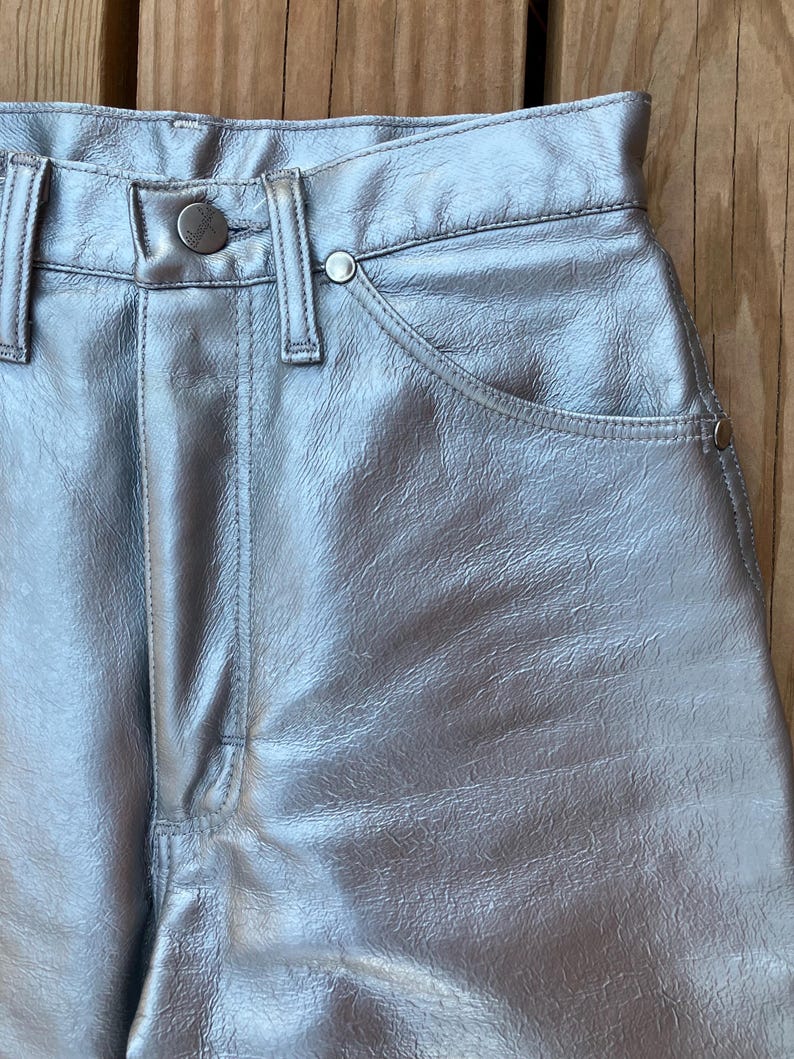Peut inclure: Pantalon argent&eacute; m&eacute;tallis&eacute; avec fermeture boutonn&eacute;e et zipp&eacute;e. Le pantalon a une conception classique &agrave; cinq poches avec des rivets et un aspect textur&eacute;. Le mat&eacute;riau a une qualit&eacute; brillante et r&eacute;fl&eacute;chissante.