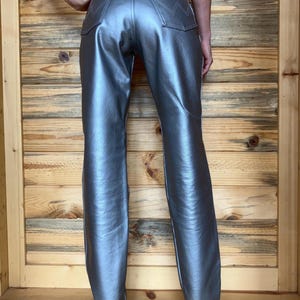 Peut inclure: Pantalon argent&eacute; m&eacute;tallis&eacute; avec une &eacute;tiquette Wrangler sur la poche arri&egrave;re. Le pantalon a une conception classique &agrave; cinq poches et un l&eacute;ger &eacute;vasement en bas. Le pantalon est fait d'un mat&eacute;riau brillant et r&eacute;fl&eacute;chissant.