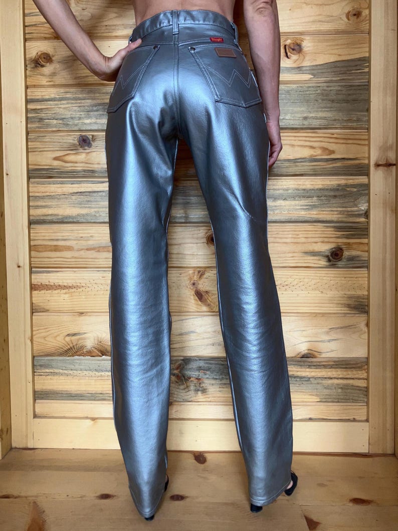 Peut inclure: Pantalon argent&eacute; m&eacute;tallis&eacute; avec une &eacute;tiquette Wrangler sur la poche arri&egrave;re. Le pantalon a une conception classique &agrave; cinq poches et un l&eacute;ger &eacute;vasement en bas. Le pantalon est fait d'un mat&eacute;riau brillant et r&eacute;fl&eacute;chissant.