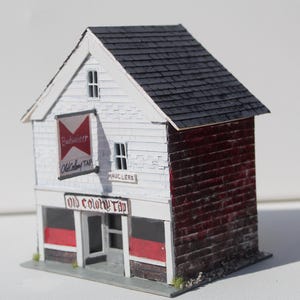 May include: A set of three ceramic mugs with a speckled, matte finish in cream, light grey, and dark grey. Each mug has a simple, minimalist design and a rounded handle. The mugs are stacked on top of each other.