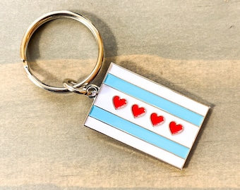 May include: A silver key chain with a blue and white enamel charm featuring the Chicago flag with four red hearts.