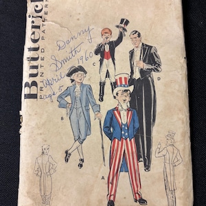 Op de afbeelding: Vintage Butterick patroon-envelop met illustraties van herenfeestkleding, waaronder een smoking en een Uncle Sam-kostuum. De envelop is verouderd, met handgeschreven notities en de tekst "Butterick Printed Patterns".