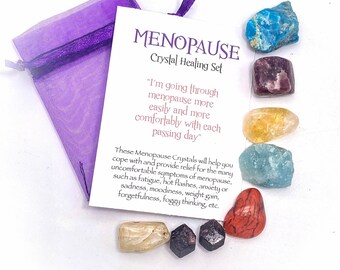 May include: A crystal healing set for menopause. The set includes a purple mesh bag, a card with text, and several colorful crystals. The card reads "MENOPAUSE Crystal Healing Set". The crystals are various colors including blue, purple, yellow, and red.
