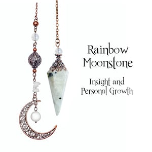 May include: A copper-colored pendulum with a faceted, white rainbow moonstone crystal and a decorative chain. The pendulum is adorned with a filigree crescent moon and the text "Rainbow Moonstone, Insight and Personal Growth."