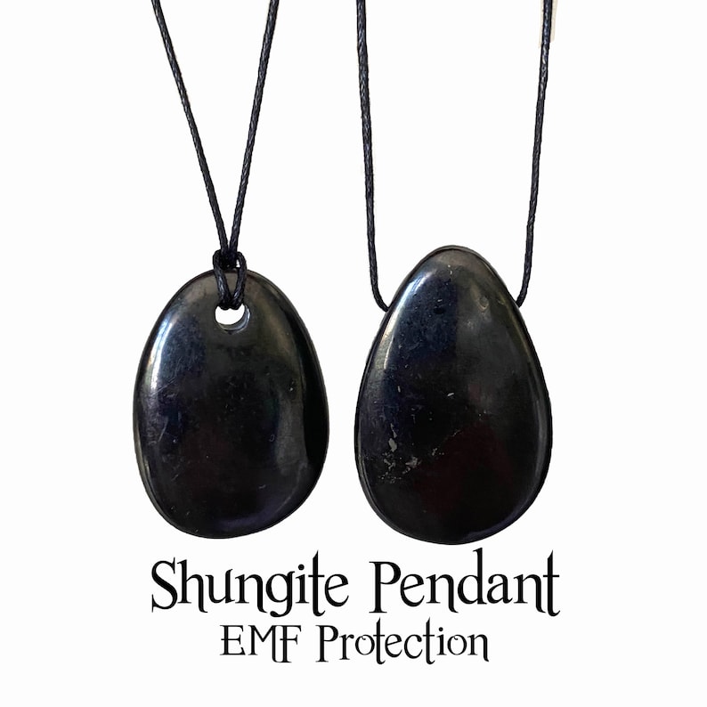 May include: Two black shungite pendants with a glossy finish, each suspended from a black cord. The pendants are oval-shaped with a smooth surface. Text at the bottom reads "Shungite Pendant EMF Protection."