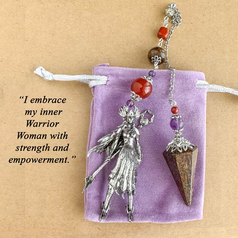 May include: A silver warrior pendant with a spear and a purple pouch. The pendant is connected to a chain with red and purple beads. The text on the left says, "I embrace my inner Warrior Woman with strength and empowerment."