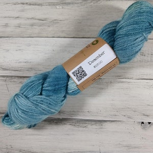 May include: A skein of blue yarn with a brown label that says "December $28.00".