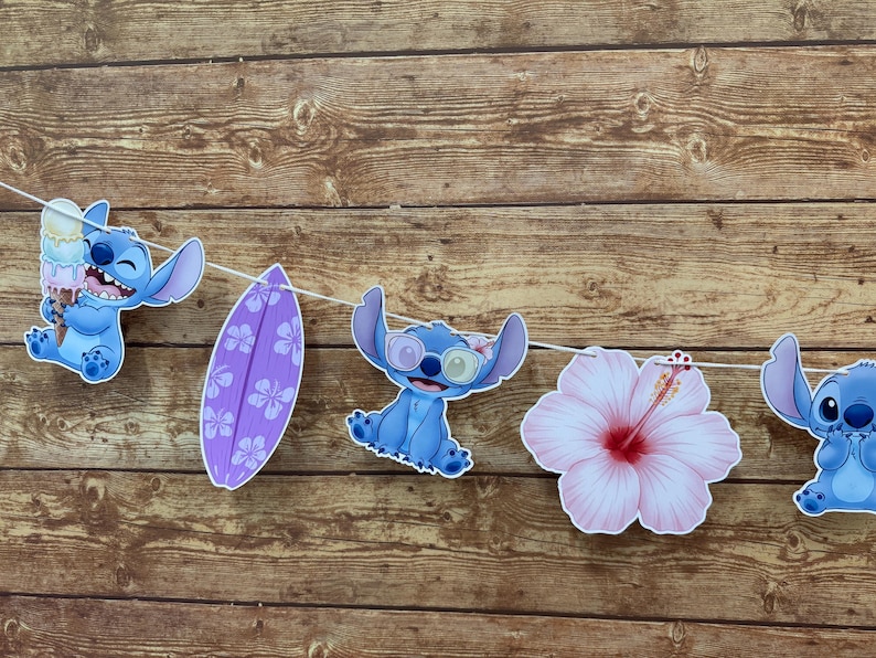 Op de afbeelding: Een slinger met uitgesneden decoraties met het personage Stitch, een paars surfplank en een roze hibiscusbloem. De Stitch-personages zijn blauw en houden ijsjes vast of dragen een zonnebril.