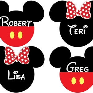 May include: Four black and red Mickey Mouse head-shaped name tags with white text. The names are Robert, Teri, Lisa, and Greg.