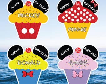 May include: Four colorful cupcake-shaped birthday decorations. Each features a character's name: Mickey, Minnie, Donald, and Daisy. The cupcakes have black mouse ears, the words "Happy Birthday", and a number representing an age.