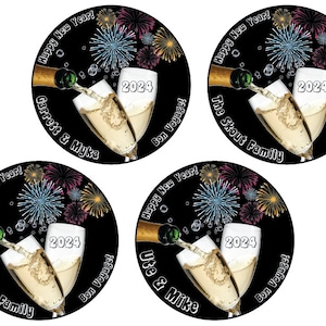 Puede incluir: Cuatro pegatinas redondas negras y doradas para la fiesta de Nochevieja con copas de champ&aacute;n brindando, fuegos artificiales y el texto "&iexcl;Feliz A&ntilde;o Nuevo!" y "&iexcl;Buen viaje!" Las pegatinas tambi&eacute;n incluyen nombres personalizados: "Garrett & Myka", "The Daley Family", "The Skout Family" y "Ute & Mike".
