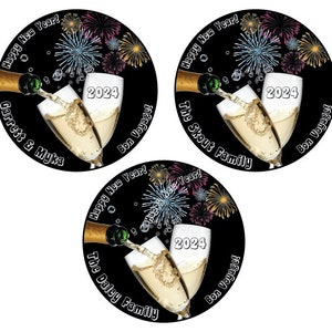 Puede incluir: Tres pegatinas circulares en blanco y negro para la fiesta de Nochevieja con una botella de champ&aacute;n que se vierte en dos copas de champ&aacute;n. Las pegatinas muestran fuegos artificiales, el a&ntilde;o 2024 y el texto "Happy New Year!" y "Bon Voyage!" La primera pegatina dice "Garrett & Myka", la segunda dice "The Skout Family" y la tercera dice "The Daley Family".