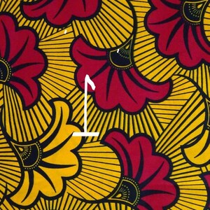 May include: A fabric pattern with a repeating design of red and yellow flowers. The flowers have a black center and are surrounded by yellow rays.