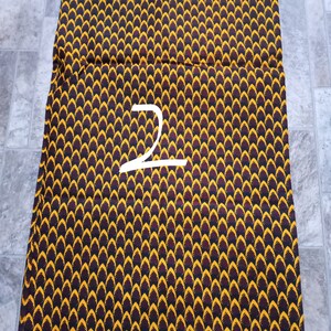May include: A stack of fabric with a black, yellow, and red pattern. The fabric is labeled "VERITABLE WAX BLOCK PRINTS HITarget 70112" and "ANTEED WAX BLOCK PRINTS HITarget 70112".