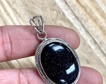 May include: A silver pendant with a black oval gemstone. The gemstone has a sparkly, speckled texture.