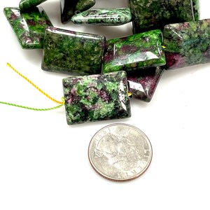 Puede incluir: Cuentas cuadradas con un patr&oacute;n verde y granate, ensartadas en hilo amarillo y verde. Se incluye una moneda como referencia de tama&ntilde;o. Las cuentas miden aproximadamente 1,5 cm cuadrados.