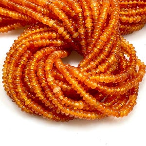 May include: A strand of orange carnelian beads, each bead is a small, round, and slightly flattened disc. The beads are strung together to form a long necklace.