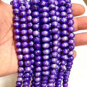 May include: A collection of vibrant, purple freshwater pearls. The pearls are oval and have a subtle iridescent sheen. The beads are strung together, creating a flowing, elegant look. Suitable for jewellery making or adding colour to any design.