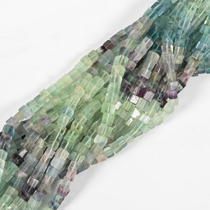 May include: A strand of green, blue, and purple fluorite beads. The beads are square and faceted, and they are strung on a clear thread.