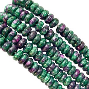 May include: Strands of gemstone beads in shades of green and purple. The beads are round with a slightly flattened shape. The colors are mixed, with some beads appearing more green and others more purple. The beads are strung together.