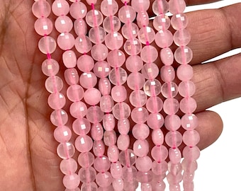 May include: Strands of faceted rose quartz beads in varying shapes and sizes. The beads are a soft pink colour and strung on pink thread. The beads are held in a hand against a white background.