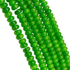 May include: Close-up of several strands of bright green beads. The beads are round with a slightly flattened shape and a glossy finish. The beads are strung together, creating a flowing, textured appearance. The background is plain white.