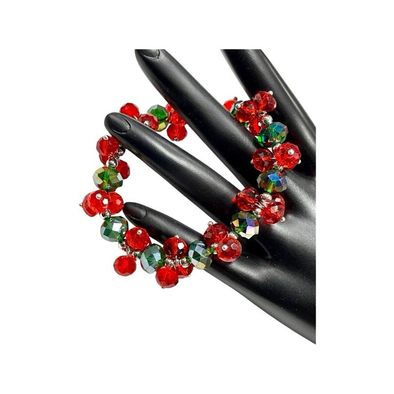 May include: A red and green beaded bracelet with iridescent crystals. The bracelet is made of small, faceted beads that are strung together on a silver wire.