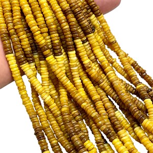 May include: Strands of yellow and brown gemstone beads. The beads are small, round, and have a polished finish. The color gradient ranges from light yellow to a deep brown. The beads are strung together, creating a flowing, textured appearance.