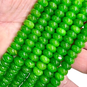 May include: Close-up of strands of bright green beads. The beads are round and have a glossy finish. The beads are strung together, creating a necklace or bracelet.